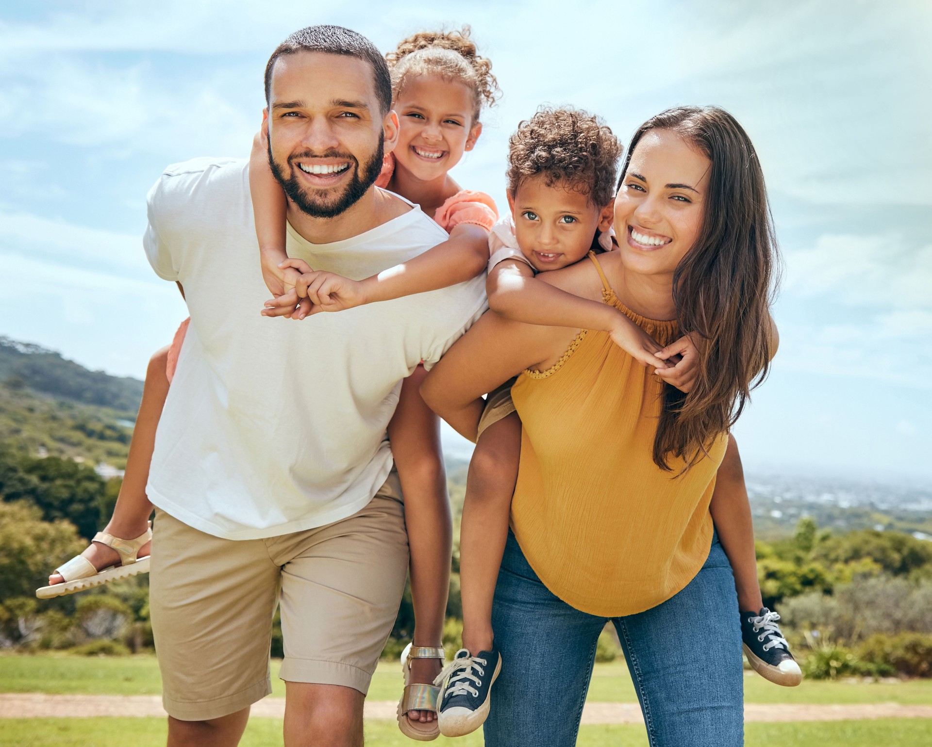 Happy family, mother and father with children on back in a nature park for bonding and relaxing in summer. Smile, mom an dad love enjoying quality time with siblings or kids outdoors for fresh air